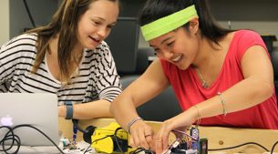 two female students building a robot together