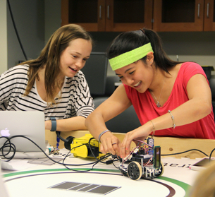 two female students building a robot together