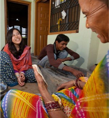female student smiling and sitting with natives in traditional garb while studying abroad