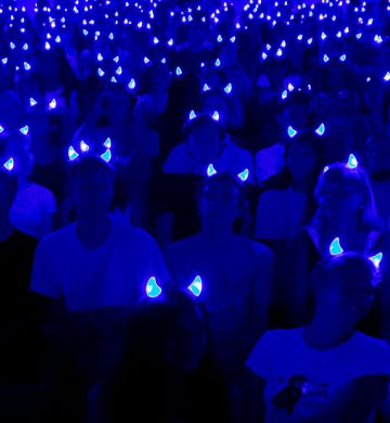 crowd of students in the dark wearing duke blue glowing devil horn headbands