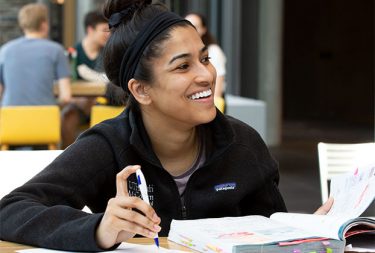 student smiling with text book