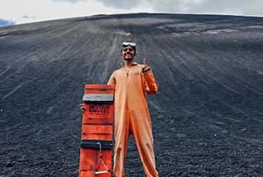 student in orange jumpsuit posing on volcanic ash